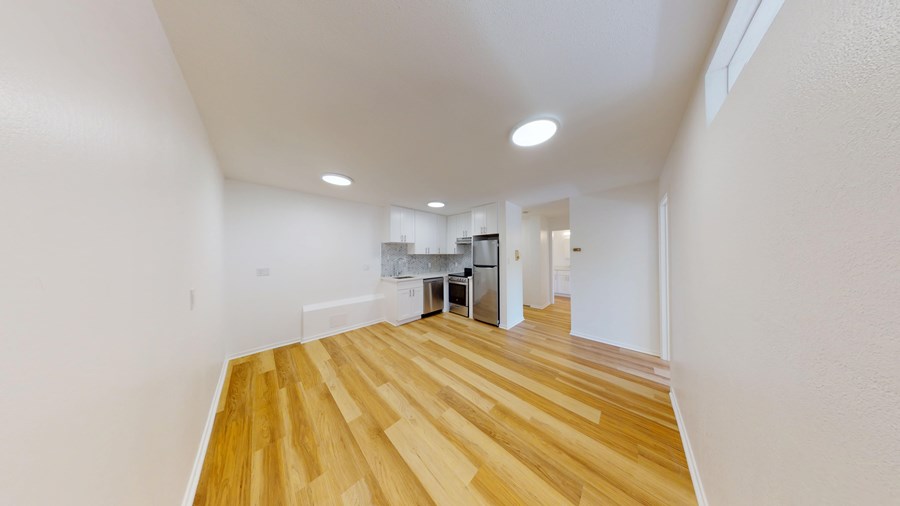 A spacious room with wooden flooring and white walls.